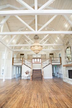 the inside of a large white building with wood flooring and chandelier hanging from the ceiling