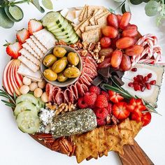 a platter filled with cheese, crackers, fruits and vegetables next to olives