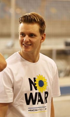 a man in a white t - shirt smiles at the camera