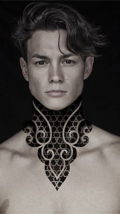 a man with no shirt wearing a black and white neck piece that has intricate designs on it