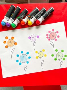 four crayon markers are sitting on top of a piece of paper with flowers drawn on it