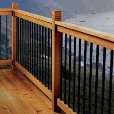 a wooden deck with railings overlooking the ocean and mountains in the distance, on a cloudy day