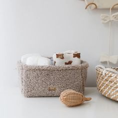 two baskets with towels in them sitting on a table next to a basket and towel rack