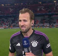 a man holding a microphone on top of a soccer field