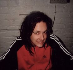 a man with long hair wearing a red jacket