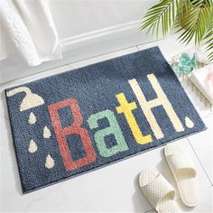 a bath mat with the word bath on it next to slippers and towels in a bathroom