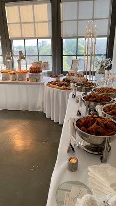 a buffet table filled with lots of food on top of a white table cloth covered table