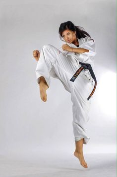 a woman is doing karate moves on a white background with her arms in the air