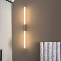 a bathroom light that is on the side of a wall next to a towel rack