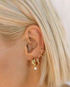 a woman with blonde hair wearing gold earrings and a star shaped earring on her left ear