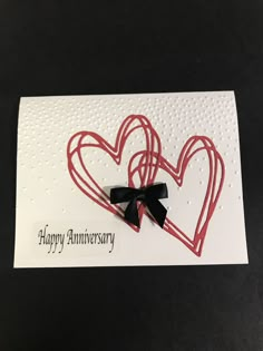 an anniversary card with two hearts and a ribbon on the front that says happy anniversary