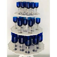 a three tiered cake with blue wine glasses on the bottom and silver rims