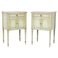 a pair of white painted wood side tables with drawers and pulls on the legs,