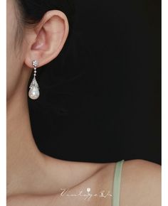 a woman wearing a pair of earrings with pearls hanging from it's ear ends