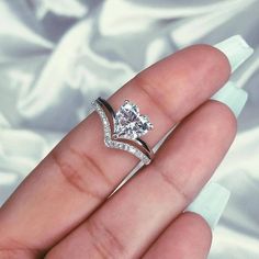 a woman's hand holding a diamond ring on top of her left finger,