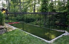 a tennis court in the middle of a yard with a net on it and some trees