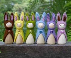 five small stuffed animals are lined up on a wooden ledge in front of some trees