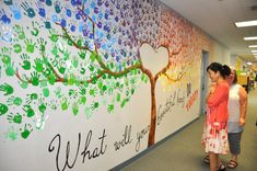 two girls are standing in front of a wall with handprints on it that says what will you do?