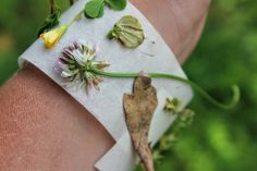 a person's arm with flowers and leaves on it that are covered in white paper