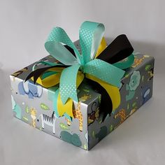 a small gift box with a green bow on it's top and giraffe print wrapping around the bottom