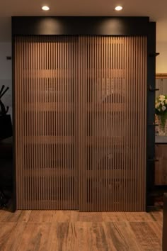 a large wooden door in the middle of a room with wood flooring and lighting