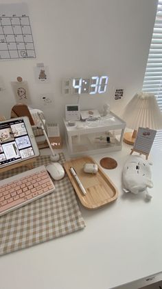 a desktop computer sitting on top of a white desk next to a clock and lamp