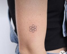 a woman's arm with a small flower tattoo on the left side of her arm