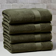 four folded towels stacked on top of each other in front of a white brick wall