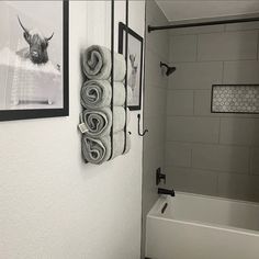 towels are hanging on the wall next to a bathtub in a white tiled bathroom