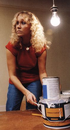 a woman sitting at a table with a can of paint