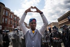 a man making a heart shape with his hands while standing in front of police officers