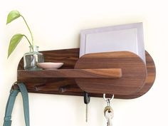 a wooden shelf with keys and a plant on it next to a pair of scissors