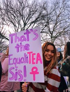 a woman holding a sign that says, that's the equal tea sis 4