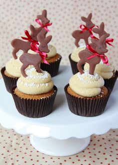 three cupcakes decorated with reindeer decorations on top of a white cake platter