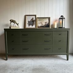 a green dresser with two pictures on top and candles in the bottom, next to it