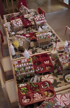 the table is set up with many different desserts and candies in trays