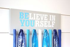 a sign that says believe in yourself hanging on a wall with blue ribbons attached to it