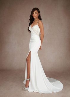 a woman in a white dress posing with her legs slited up and wearing high heels