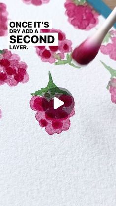 someone is painting flowers on paper with a brush