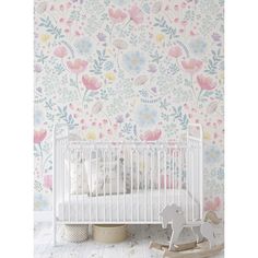 a white crib in front of a floral wallpaper