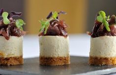 three small desserts are sitting on a black platter with green garnishes