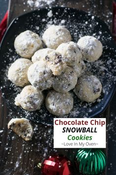 chocolate chip snowball cookies on a black plate with christmas ornaments in the foreground