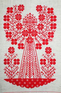 a red and white piece of art with flowers in the center on a linen background