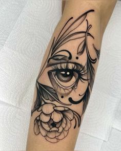 a woman's leg with an eye and flower tattoo design on the side of her leg