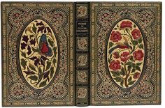 an old book with floral designs on the front and back cover, opened to reveal a page