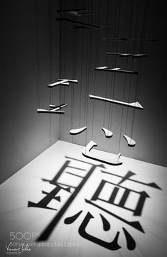 an artistic display with chinese calligraphy on the floor and suspended shoes in the air