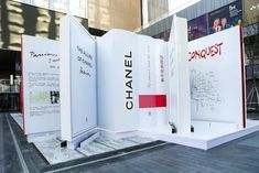 three large white panels with red and black writing on them in front of a building