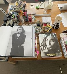 an open book sitting on top of a wooden table next to a cup and other items