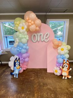 balloon arch decorated with cartoon characters and one word on the top, surrounded by balloons