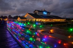 people are walking on the boardwalk covered in christmas lights